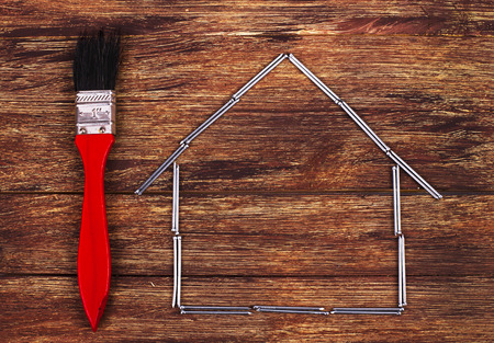 This is an overhead photo of nails in the shape of a home building and brush. There is a lot of space for copy inside the house shape.の写真素材