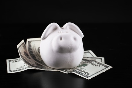 Piggybank full of dollar bills, isolated on black.の写真素材