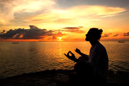 Yoga scene man silhouette in sunset background.の写真素材