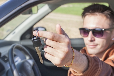 Young man in car showing keysの写真素材