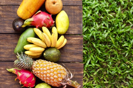 Mixed exotic fruits on wood background. Healthy eating, dieting. Top view with grass copy spaceの写真素材