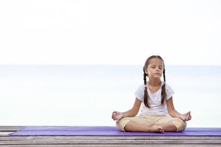 Child doing exercise on platform outdoors. Healthy lifestyle. Yoga girlの写真素材