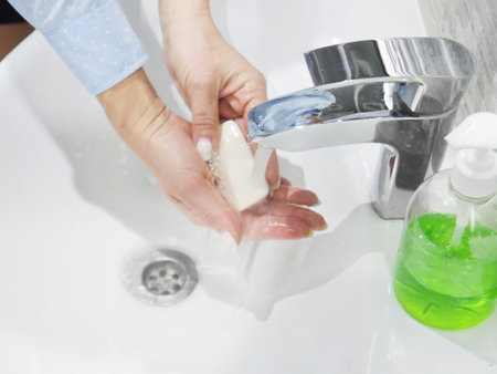 hand washing with soap or gel under running water in the washbasin, cleanliness and hygiene, womans...