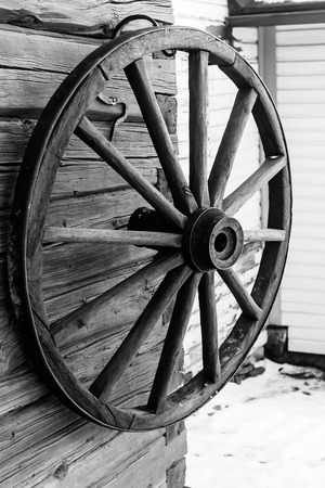 An old wooden carriage wheel hanging on the wall.の写真素材