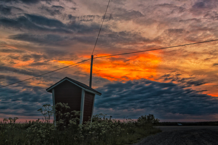 An old milk shelter in front of the telephone lines and a beautiful sunset in the Northern Finland.の写真素材
