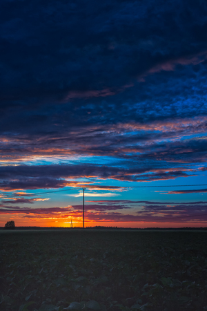 A dramatic summer sunset in the Northern Finland. The old telephone lines are crossing the evening sky.の写真素材