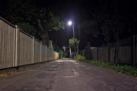A narrow street in the area of Nomme in Tallinn, Estonia on an autumn night, The lamp lights share light to the empty alley.の写真素材