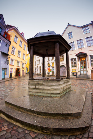 An old well in the middle of the old town of Tallinn, Estonia. The well is on a square surrounded by pittoresque old buildings.の写真素材