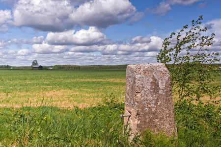 An old stone pole used for the rails of an old bridge in the rural Finland on a windy summer day.の写真素材