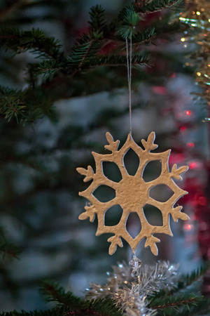 A snow flake made of fabric hanging on a traditional Christmas treeの写真素材