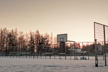 The town basketball field is covered with heavy snow at the rural town of Oulainen, Finland. The sun is setting early in this midwinter day.の写真素材