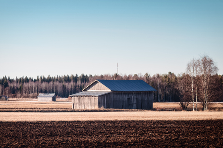 The old barn houses bathe in the springtime sun at the Northern Finland. The sun starts to warm up the frozen ground.の写真素材