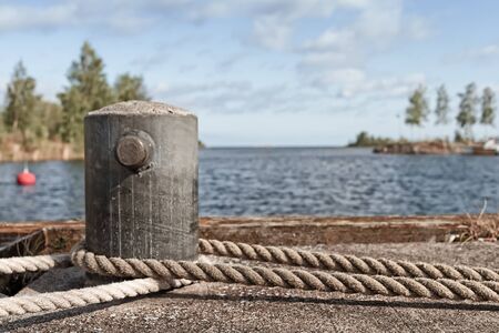 An old metal bollard on a pier at the fishing harbour of the town of Kalajoki, Finland. The ropes belong to an old galeas at the harbour.の写真素材