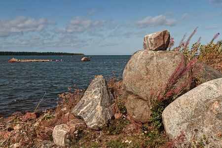 A pile of large rocks by the sea at the fishing harbour of Kalajoki, Finland. The wind is blowing hard from the sea and bending the willowherbs on the shore.の写真素材