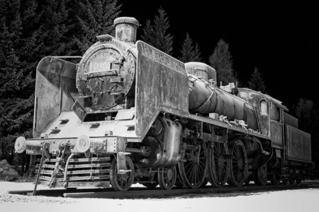 An old steam engine covered in frost on a very cold winter night at a rural town in Finland.