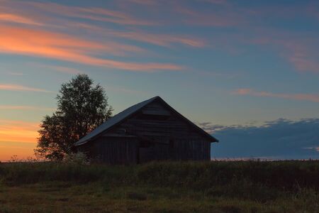 An old barn house against a beautiful midsummer sunset at the rural Finland.の写真素材
