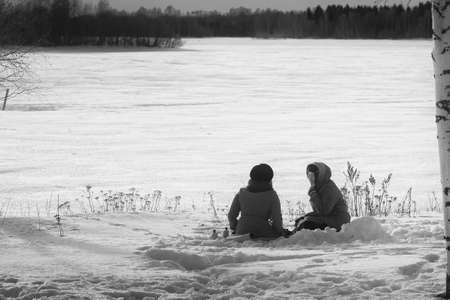 Two young women having a picnic on the frozen beach. The weather is cold but the sun is warm enough...