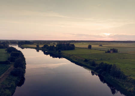 The beautiful sunset reflects on the still water of the river. The mist rises slowly on the horizon.の写真素材