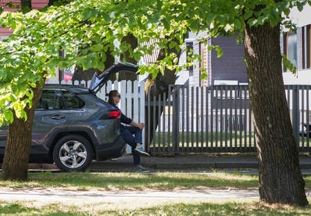 A woman is having a break by sitting in the booth of her car on a beautiful summer day.の写真素材