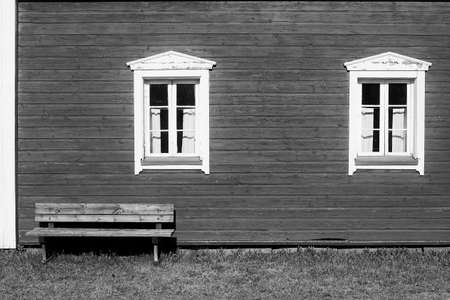 An exterior of an old wooden house on a summer day. The wooden bench is perfectly situated in the warm sunny spot.の写真素材