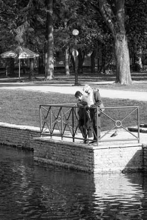 A couple is standing by the lake and looking into the water. Maybe they are looking for fish.の写真素材