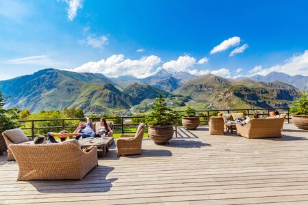 STEPANTSMINDA, GEORGIA - september 15, 2018: Beautiful view from terrace Rooms Hotel Kazbegi of the high mountain top Kazbek, Caucasus mountains and Gergeti Trinity Church Tsminda Sameba.のeditorial素材
