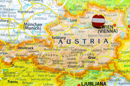 Austria national flag pinned on Europe map. Macro Close up picture of country on a colorful and Blurry World Map Globe with focus to capital Vienna. Push pin on map, marker of destination.の写真素材