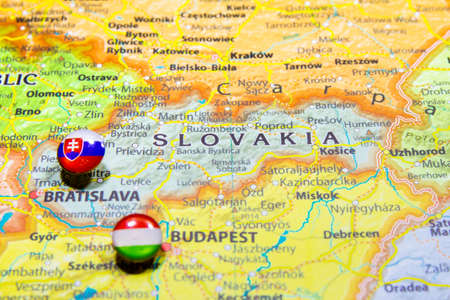 National flag Slovakia pinned on political Europe map. Macro Close up picture on a colorful and blurry world atlas. Capital country - Bratislava. Push pin marker of destination.の写真素材