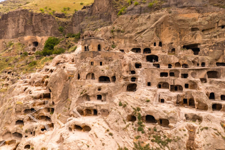 Aerial top view of Vardzia city on sunny summer day. Ancient cave monastery in Erusheti Mountain rocks at Kura River. Monument of medieval Georgian architecture, carved in rough rock. Georgia, Europeの写真素材
