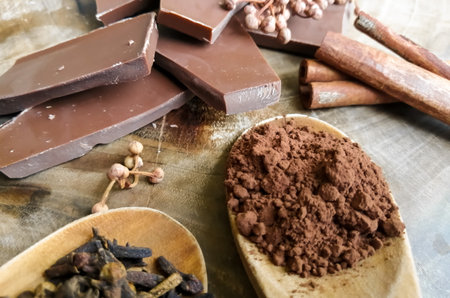 On the table pieces of chocolate, cocoa in a spoon and spices