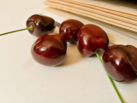 On a white background, cherries next to the book, close-upの写真素材
