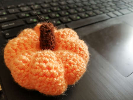 On an open laptop is a pumpkin knitted made with his own handsの写真素材