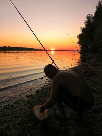 A man on the bank of the river catches fishの写真素材