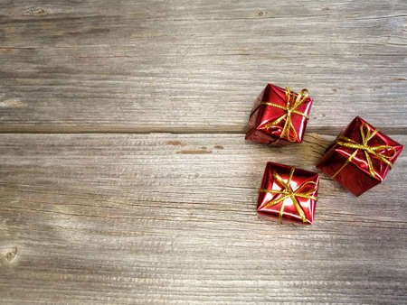 Red little giveas on a wooden table. Bandaged with a bow. Christmas and New Year.の写真素材