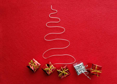 Gifts under the Christmas tree made of silver wire on red felt. Christmas and New Year.の写真素材