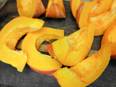 On a wooden board, a pumpkin is cut into slices. Bright autumn colors - a delicious harvest.の写真素材