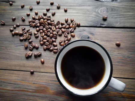 A cup of Americano on a wooden table. Coffee beans are scattered nearby.の写真素材