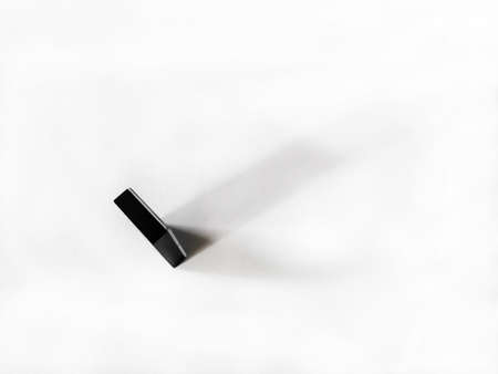 One domino chip on a white background casts a shadow.の写真素材
