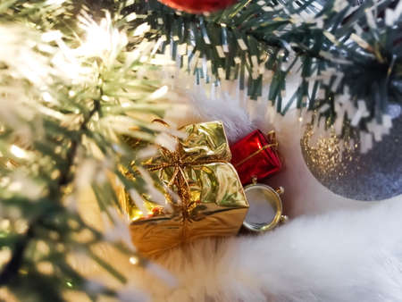 Under the Christmas tree on the faux fur is a gift in yellow packaging. Christmas and New Year.の写真素材