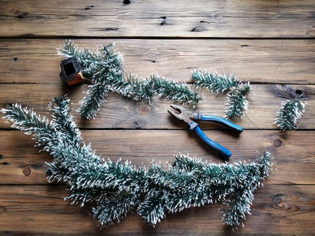 Making a Christmas garland with your own hands from artificial spruce branches. On the wooden table are twigs, pliers, wire.の写真素材