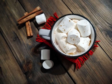 Cocoa with marshmallow in a mug on a wooden table. Next to a cup of cinnamon and marshmallows.の写真素材