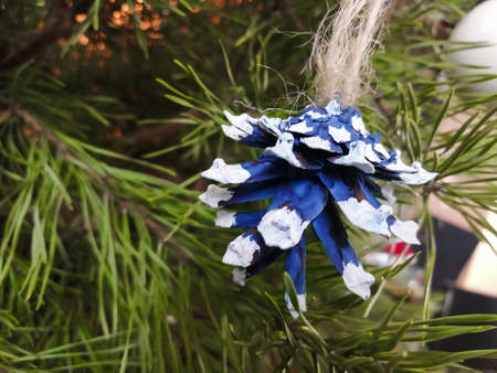 Toy on the Christmas tree - painted cone hangs on a spruce branch. Simple Christmas decorations. Christmas and new yearの写真素材