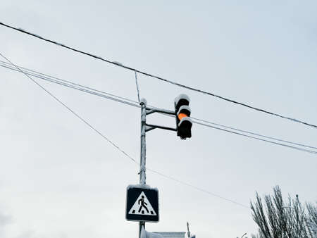 Traffic light and pedestrian crossing sign on a pole against the sky. Winter industry of the city.の写真素材