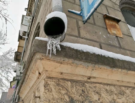 Zholob, gutter on the house with icicles in winter. The water in the gutter froze in the winter.