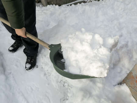 A person removes snow with a shovel for snow. Winter. Snow removal in winter - clean the paths.の写真素材