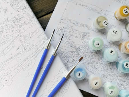 The artist's brushes and bright colors in jars for drawing on the picture by numbers or coloring by numbers. top view.の写真素材