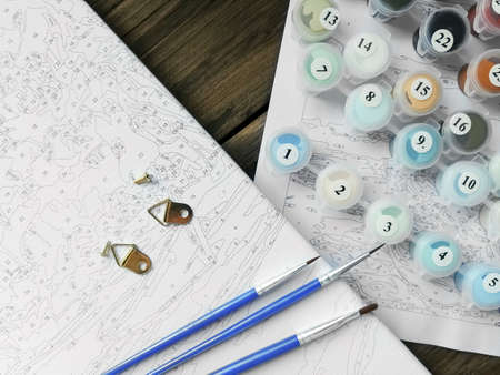 The artists brushes and bright colors in jars for drawing on the coloring by numbers or picture by numbers. Top viewの写真素材