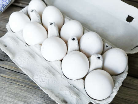 Homemade chicken eggs in a tray. 10 chicken eggs in a tray on a wooden table. Dirty chicken eggs. Photo from top to bottom. white eggshells. Healthy homemade eggs.の写真素材