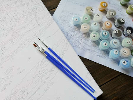 The artist's brushes and bright colors in jars for drawing on the picture by numbers or coloring by numbers. top view.の写真素材