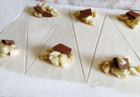 Filling chocolate and banana in triangles for croissants. Making croissants. Homemade croissants. A series of photos.の写真素材